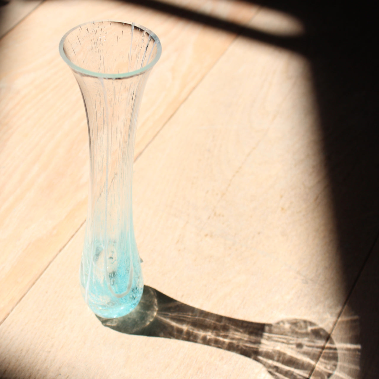 tall and narrow clear glass vase with turquoise details at the base by Cornish glass artist Helen Eastham 