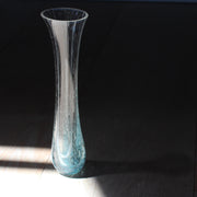 a tall and narrow clear glass vase with turquoise details at the base by Cornish glass artist Helen Eastham.