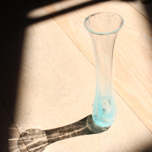 tall and narrow clear glass vase with turquoise details at the base by Helen Eastham, Cornish glass artist.