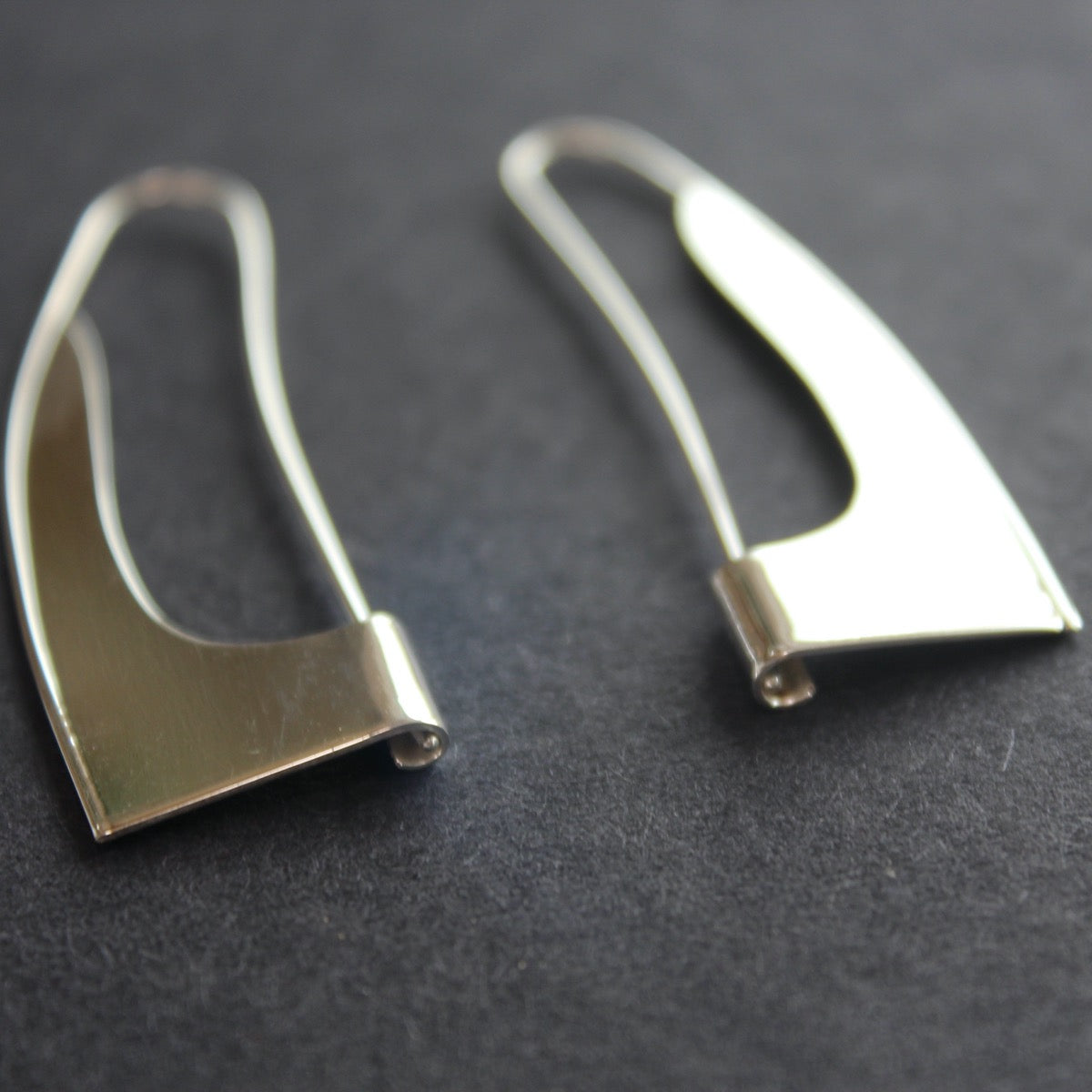 curved silver earrings in the shape of a sail