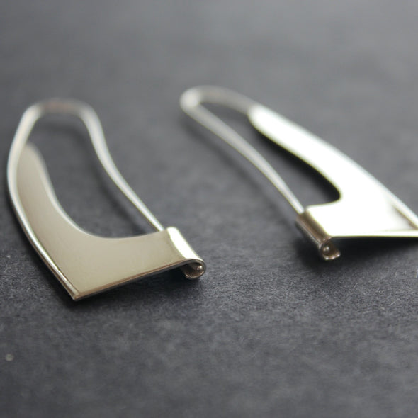 curved and cut out silver earrings in the shape of a sail