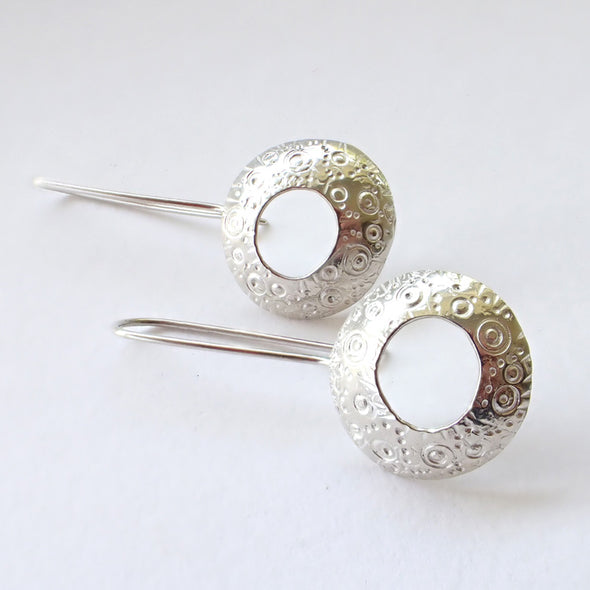 silver drop earrings with a hollow centre and a delicate pattern of circles by Ann Bruford 
