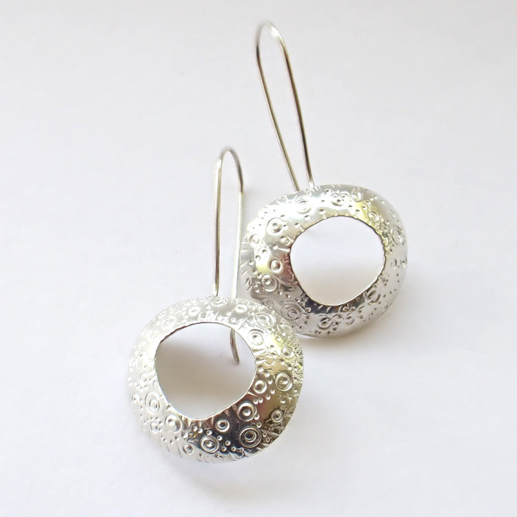 silver drop earrings by Ann Bruford with a hollow centre and a textured surface pattern