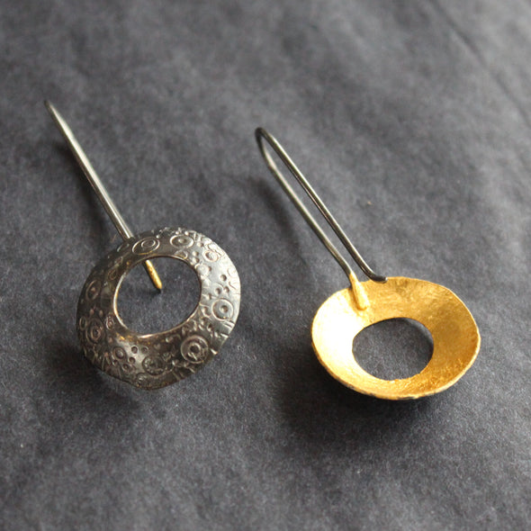 a pair of circular drop earrings with gold on the inside and a textured dark finish on the outside they are by Ann Bruford, Devon jeweller 