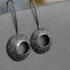 circular drop earrings with gold on the inside and a textured dark finish on the outside they are by  jeweller Ann Bruford