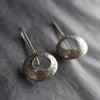 a pair of dark silver drop earrings with a hollow centre by UK jeweller Ann Burford
