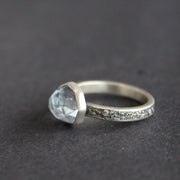 Textured silver ring with pale blue stone on a grey surface 