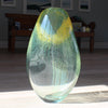 green and yellow glass vessel by glass artist Benjamin Lintell in the sunshine 