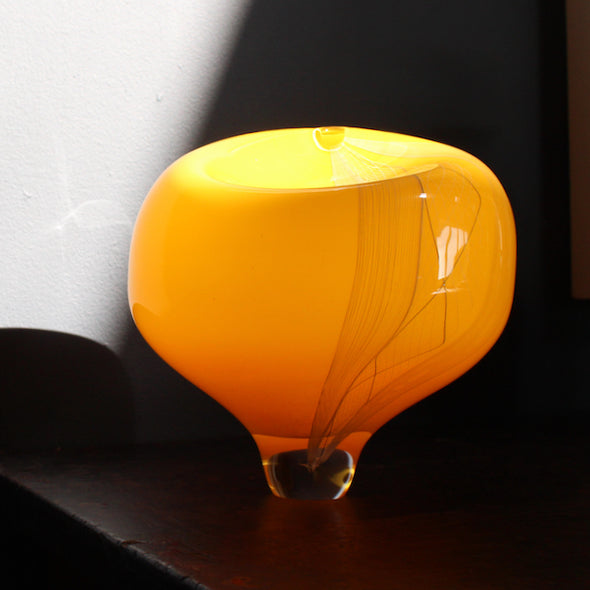 round yellow glass vessel on a clear base by Benjamin Lintell