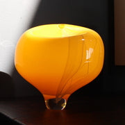 a round yellow glass vessel on a clear base by Benjamin Lintell.