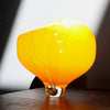 round yellow glass vessel with grey lines on a clear base by Benjamin Lintell photographed in the sunshine 