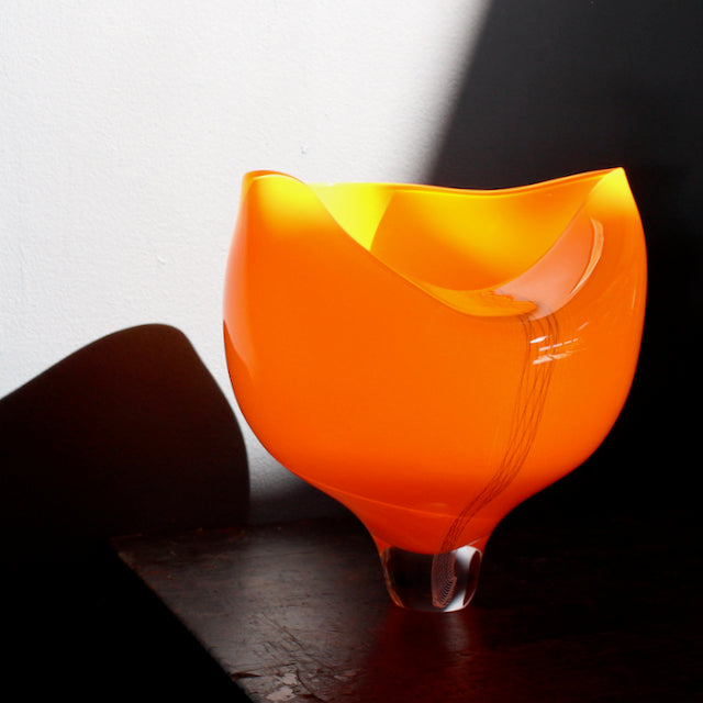 buckled shape orange blown glass vessel with line detail to the front made by UK glass artist Benjamin Lintell.