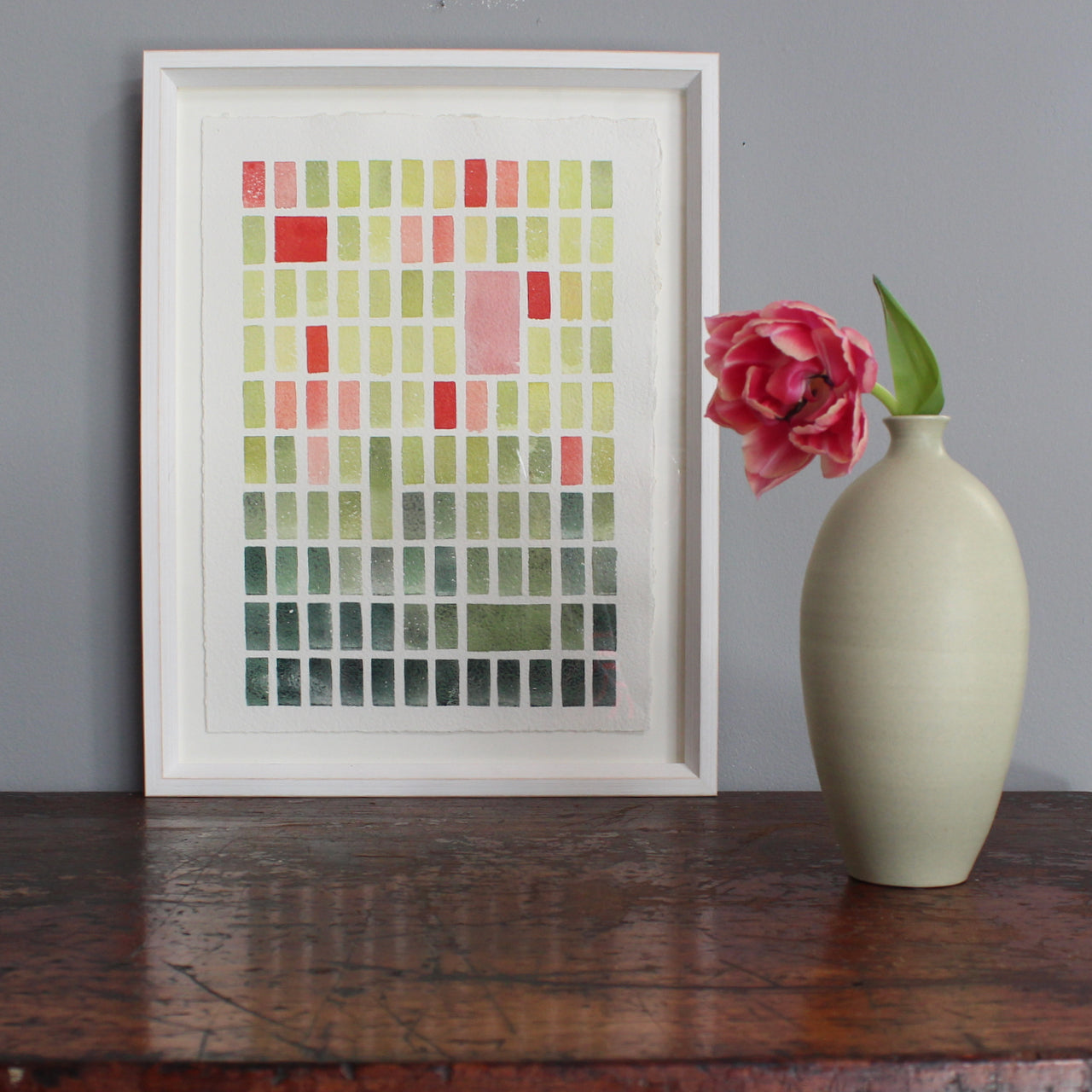 Abstract painting by David Muddyman of pink, yellow and green rectangles  framed next to pale green bottle with a pink tulip in it