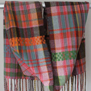 Handwoven scarf with orange, pink and green hanging over a display rail 