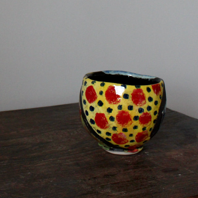 a brightly coloured small ceramic bowl in yellow and red by UK potter John Pollex.
