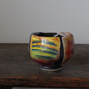 a ceramic teabowl in red, green and yellow by leading UK potter John Pollex .