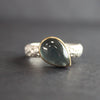 silver ring with teardrop shaped blue grey stone in gold setting by Carin Lindberg jewellery designer