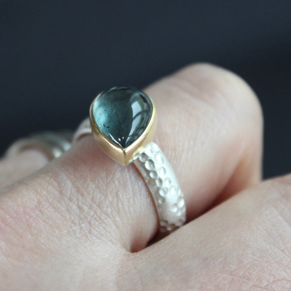 silver ring with teardrop shaped blue grey stone in gold setting by Carin Lindberg jeweller