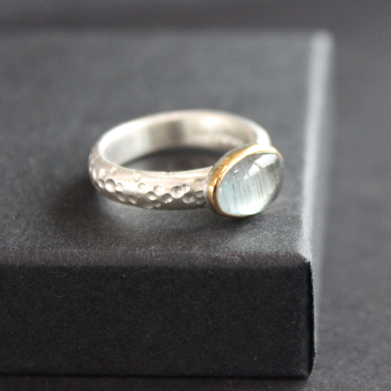 Moss aquamarine (oval) set in gold on textured ring in brushed silver by Carin Lindberg