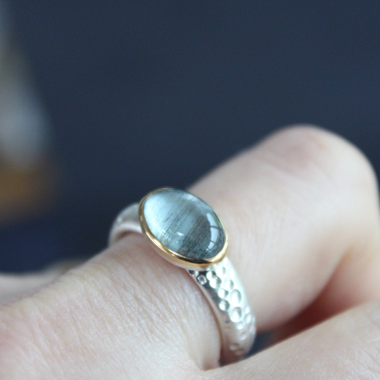Moss aquamarine (oval) set in gold on textured ring in brushed silver by Carin Lindberg on finger
