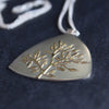 Close up of plantae flat pendant in silver with gold tree detail by Beverly Bartlett