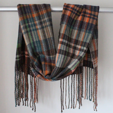 Handwoven scarf with orange, brown and blue colours hanging over a display rail 
