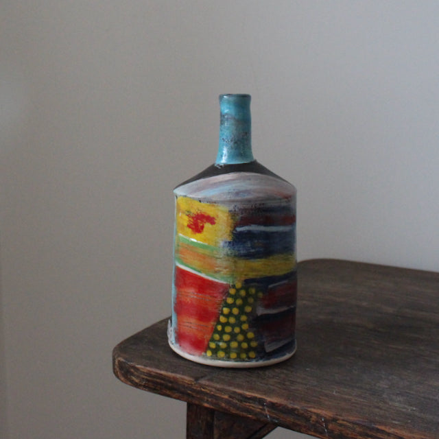 a multi-coloured ceramic bottle with a blue neck by John Pollex