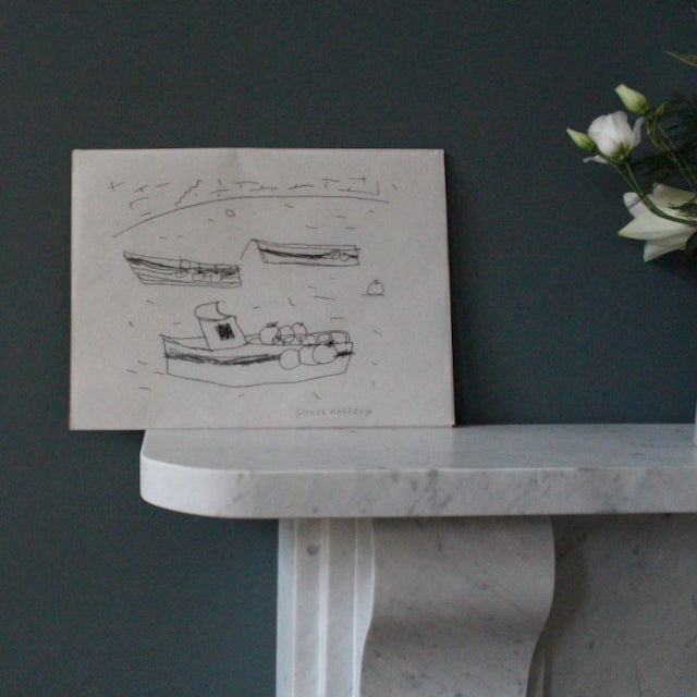 drawing in black ink by Sophie Harding of three boats in a harbour it is resting on marble mantlepiece  next to  some flowers 
