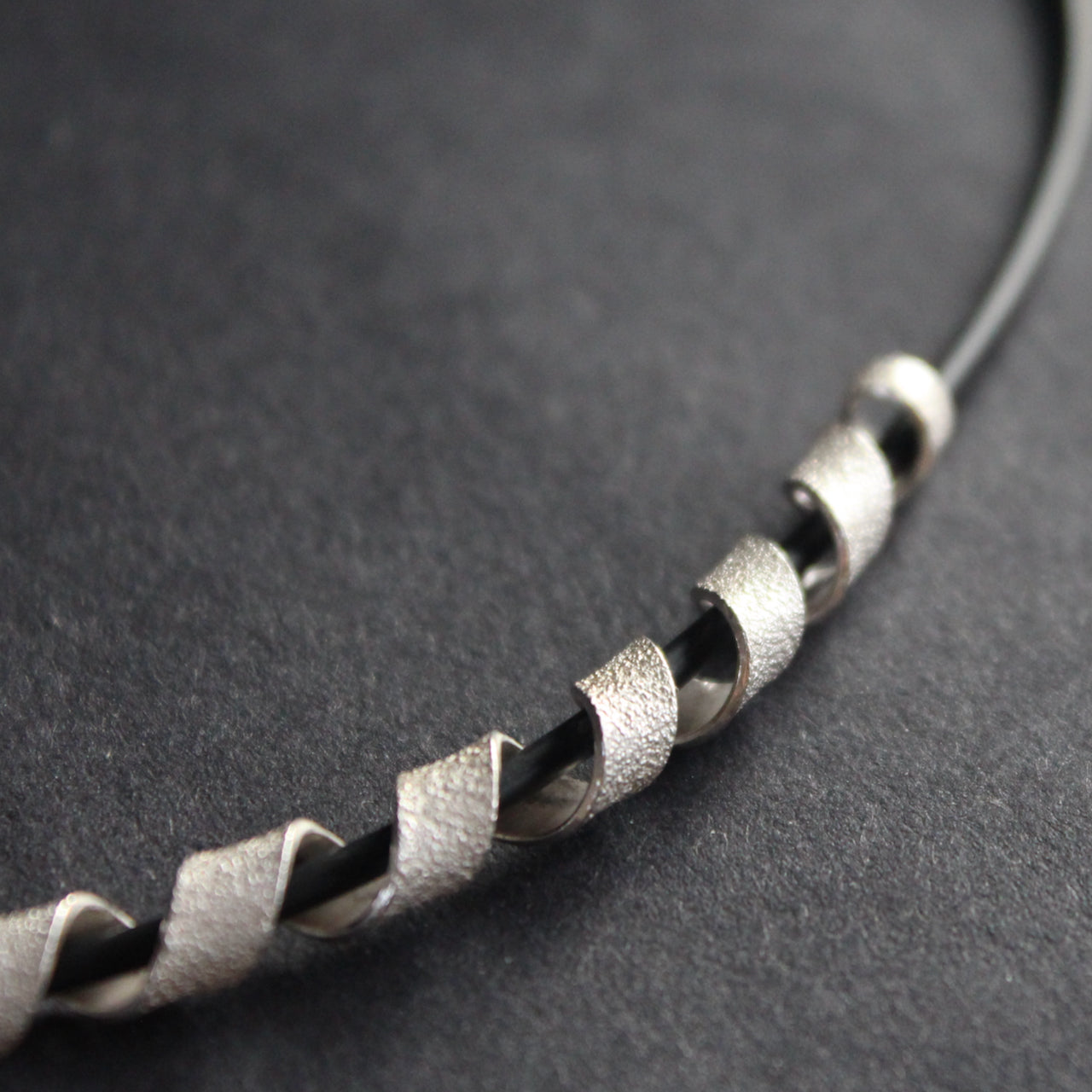 close up detail of silver helix twisted necklace on black leather band by Beverly Bartlett.