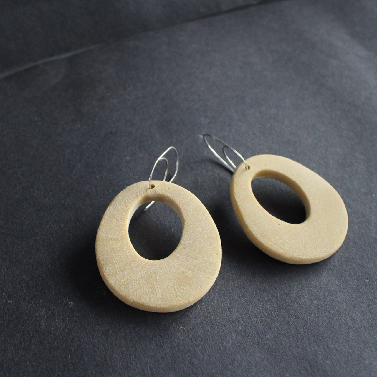 a pair of oval shaped pale yellow earrings with hole in the middle  by jewellery designer Clare Lloyd 