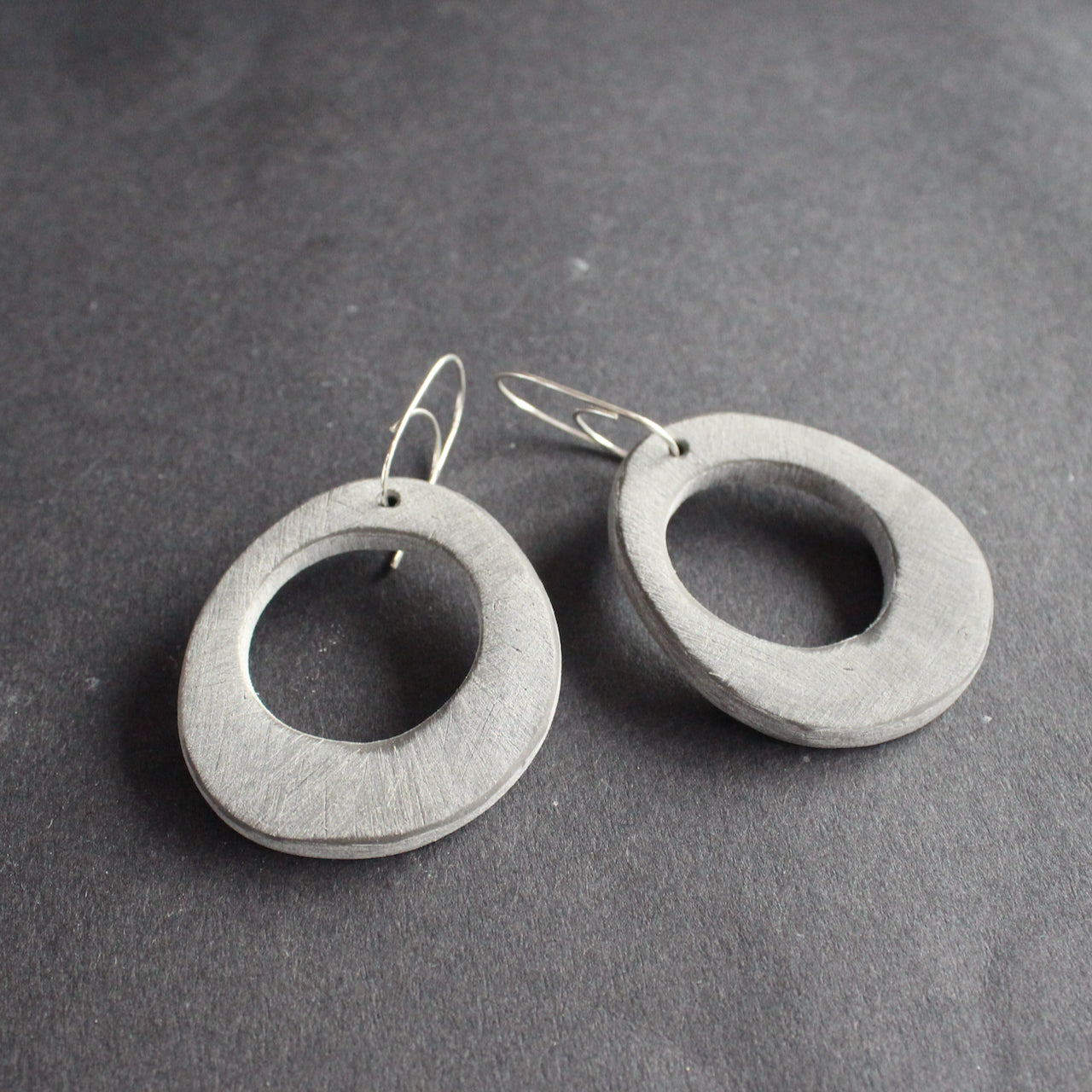 oval shaped pale grey earrings with hole in the middle  by jewellery designer Clare Lloyd