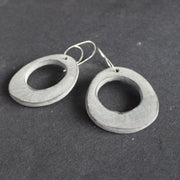 a pair of oval shaped pale grey earrings with hole in the middle  by jewellery designer Clare Lloyd.