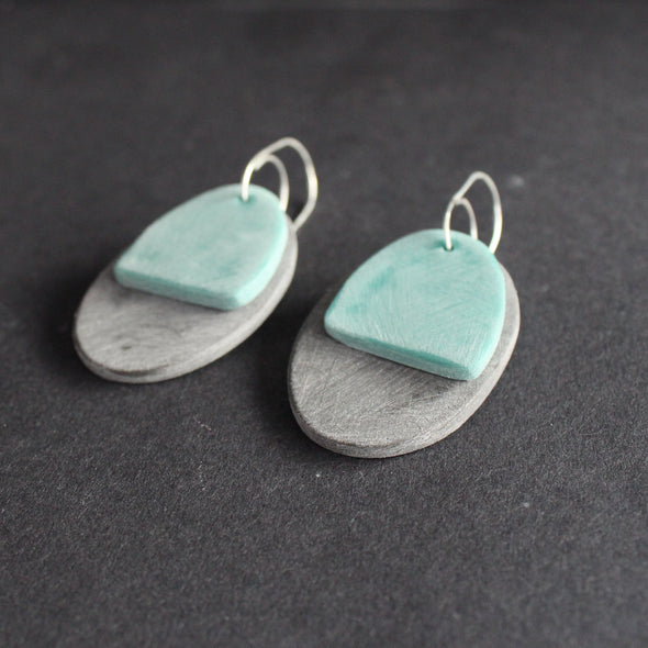 a pair of oval shaped earrings in grey and green by jewellery designer Clare Lloyd 