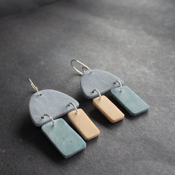 a pair of earrings in blue, turquoise and pale yellow by jewellery designer Clare Lloyd 