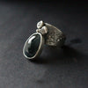 textured and embellished silver  ring with a large dark blue green stone  by jeweller Carin Lindberg.