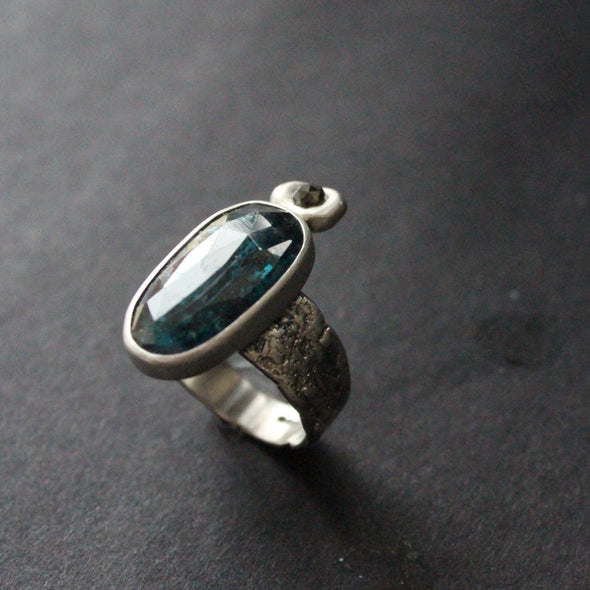 a textured silver  ring with a large dark blue green stone and smaller brown diamond by jeweller Carin Lindberg
