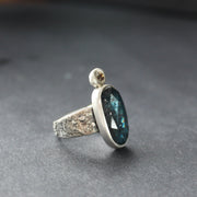 textured silver  ring with a large dark blue green stone and smaller brown diamond by jeweller Carin Lindberg.
