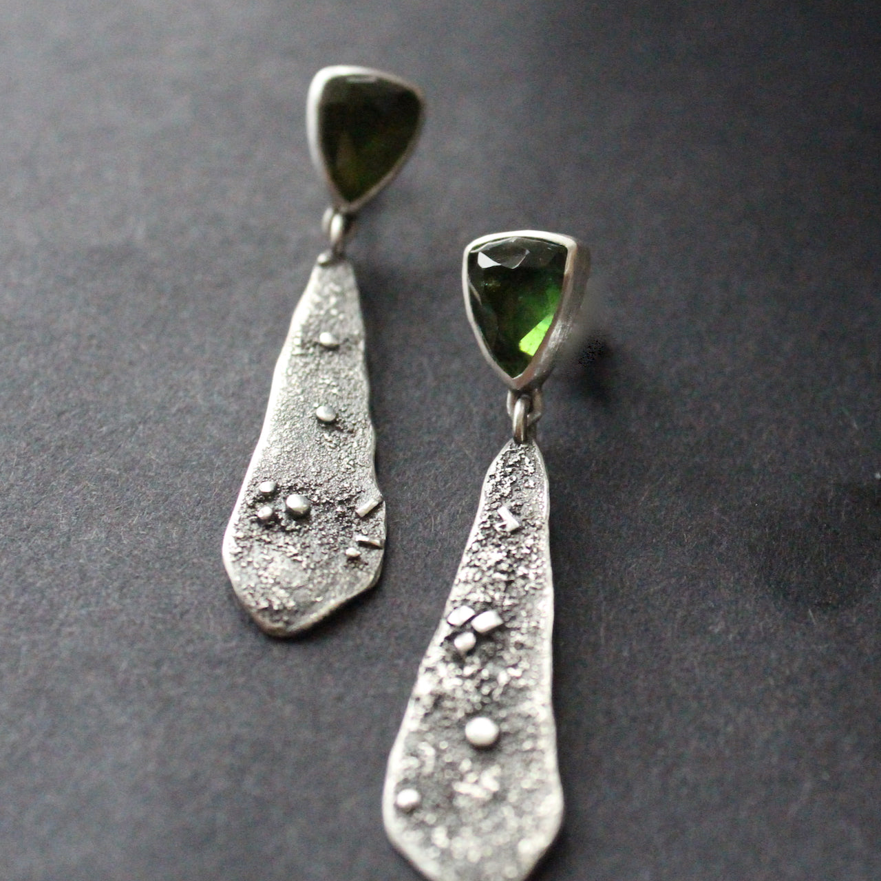 textured silver earrings with a dark green stone by jeweller Carin Lindberg.