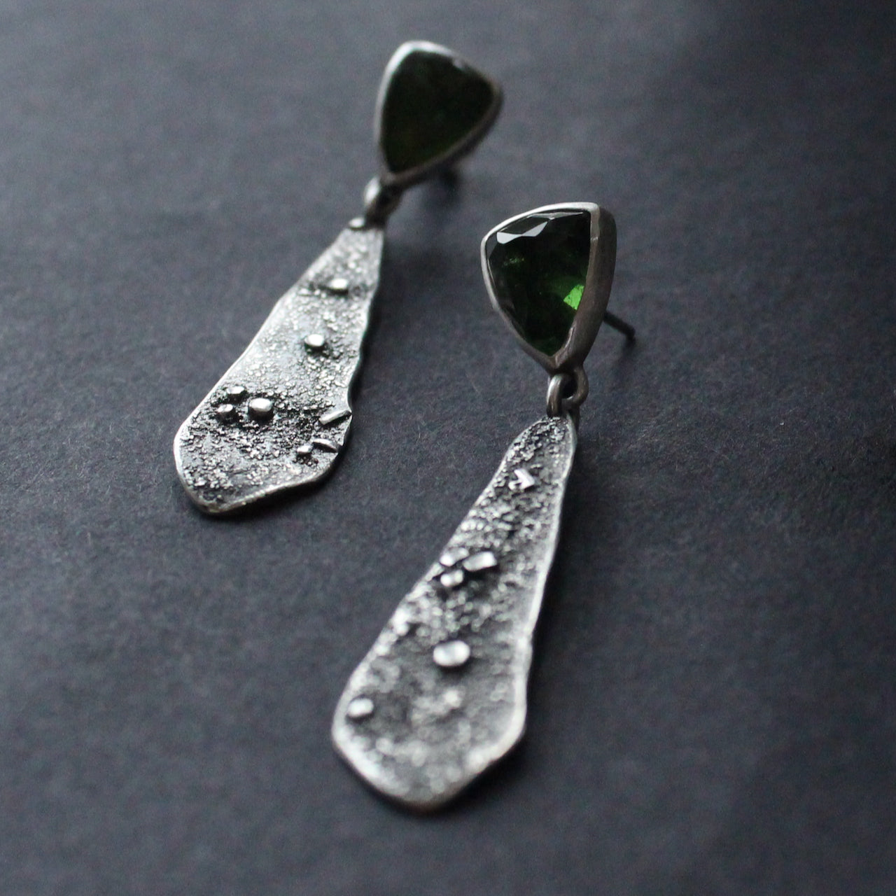 a pair of textured silver earrings with a dark green stone by Cornwall based  jeweller Carin Lindberg