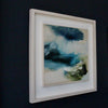 abstract painting in blues and greens in a white frame on a dark blue wall it is by artist Tara Leaver.