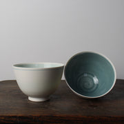 a pair of small white porcelain bowls one with pale turquoise and one with mid blue interior  by Kathryn Sherriff of By the Line Pottery.