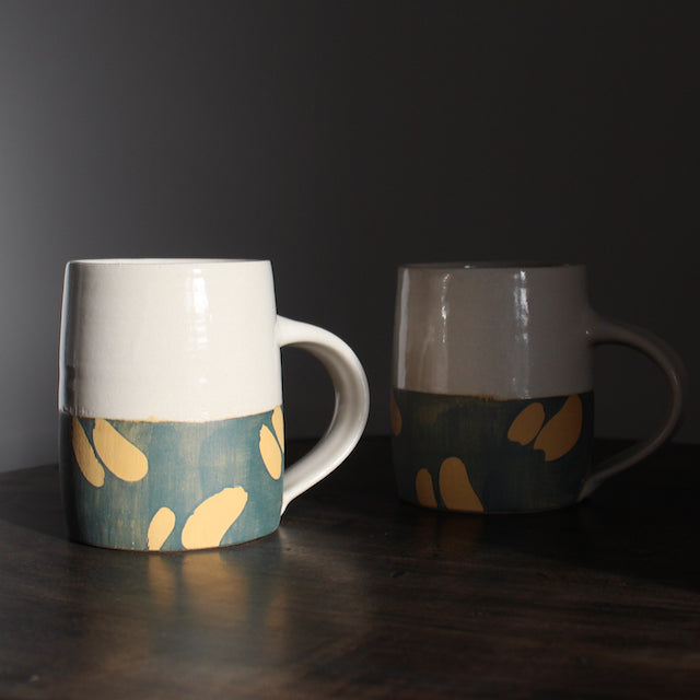 two ceramic mugs with bottom half glazed in blue with abstract yellow marks by ceramicist Kate Welton.