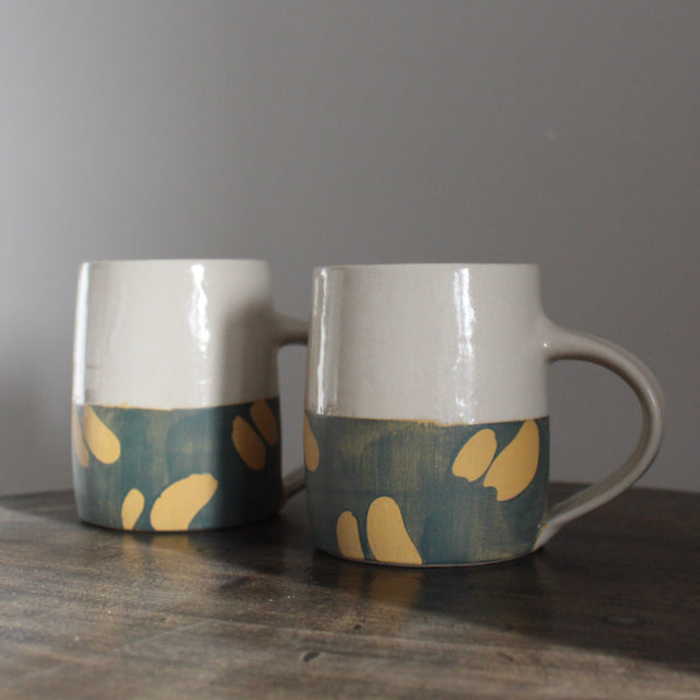a pair of ceramic mugs with bottom half glazed in blue with abstract yellow marks by UK ceramicist Kate Welton