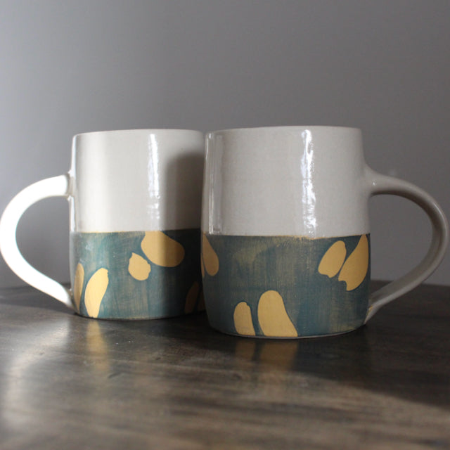 pair of ceramic mugs with bottom half glazed in blue with abstract yellow marks by ceramicist Kate Welton.