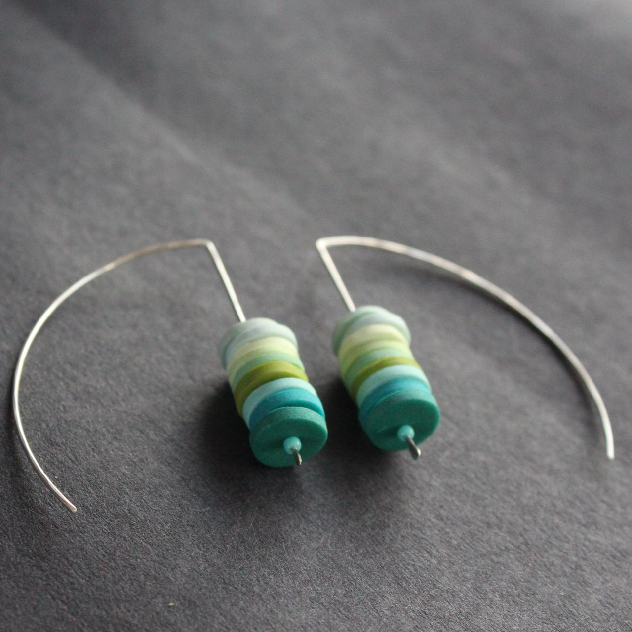 earrings made of small discs on top of each other in shades of blues and green by jewellery designer Clare Lloyd