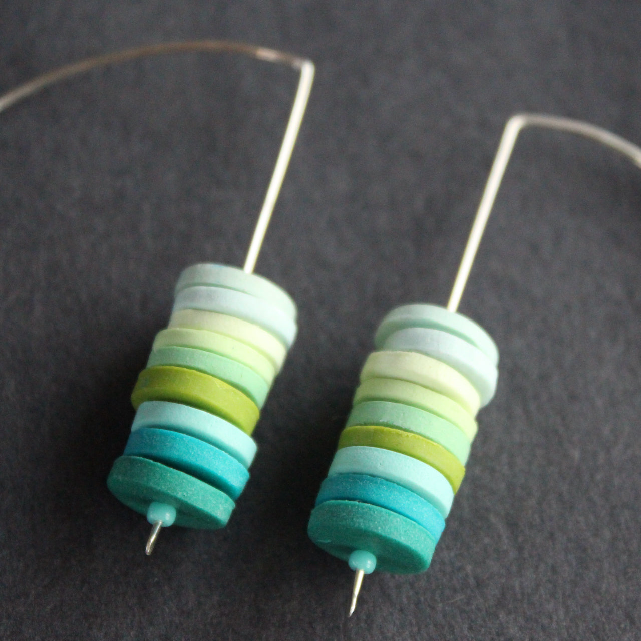 pair of earrings made of small discs on top of each other in shades of blues and green by UK jewellery designer Clare Lloyd