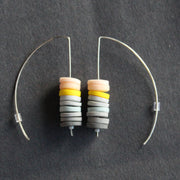 a pair of earrings made of small discs on top of each other in shades of grey and pink by Uk based jewellery designer Clare Lloyd 
