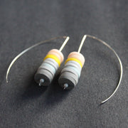 a pair of earrings made of small discs on top of each other in shades of grey and pink by jewellery designer Clare Lloyd 