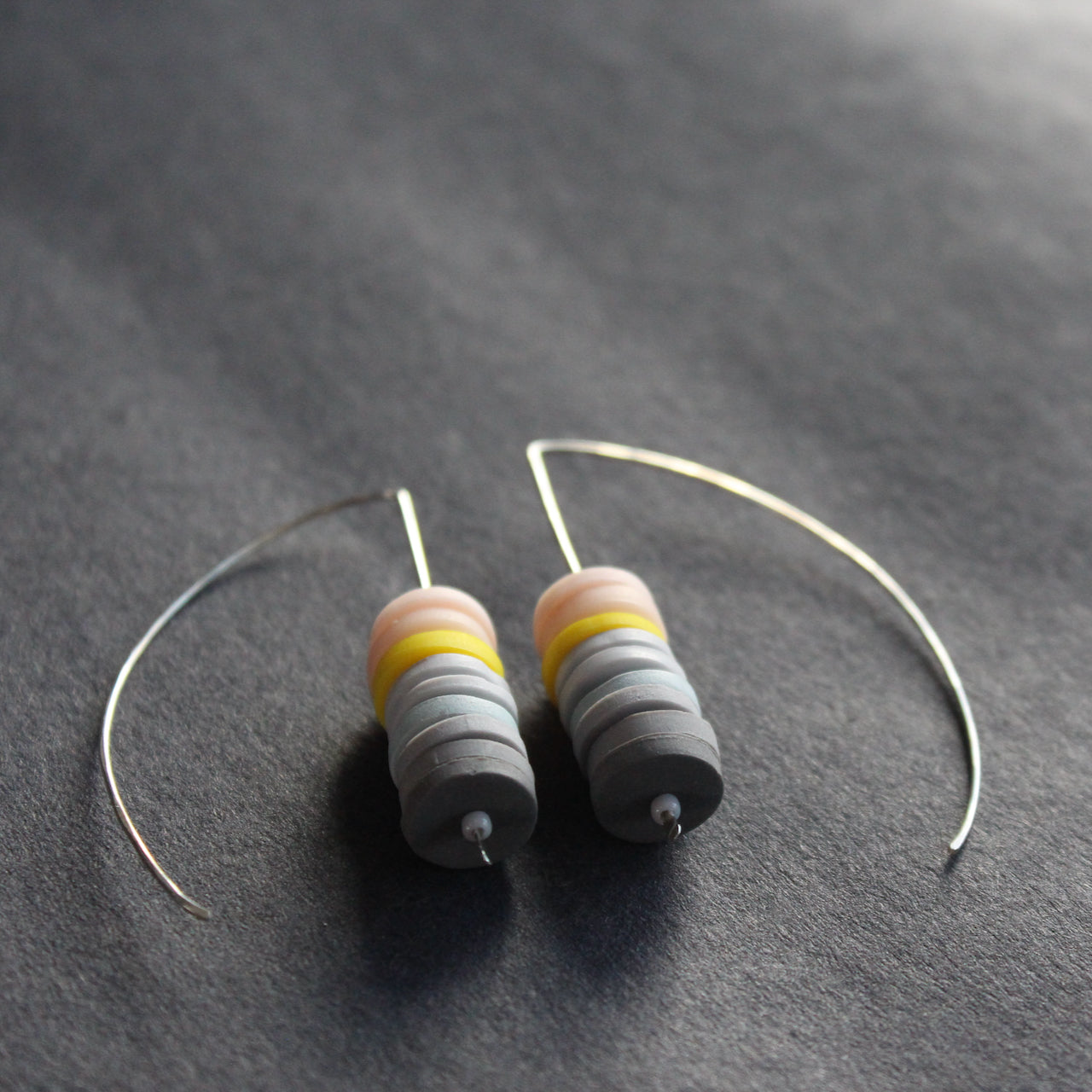 earrings made of small discs on top of each other in shades of grey and pink by jewellery designer Clare Lloyd 