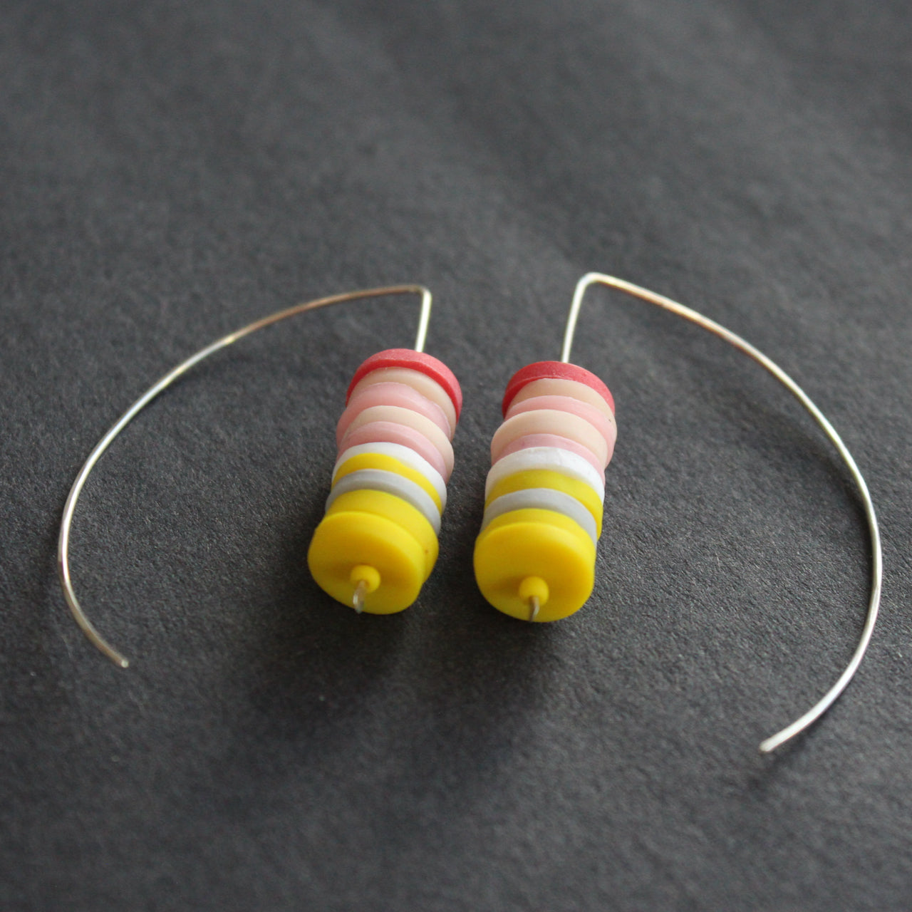 earrings made of small discs on top of each other in yellow and shades of pink by jewellery designer Clare Lloyd.